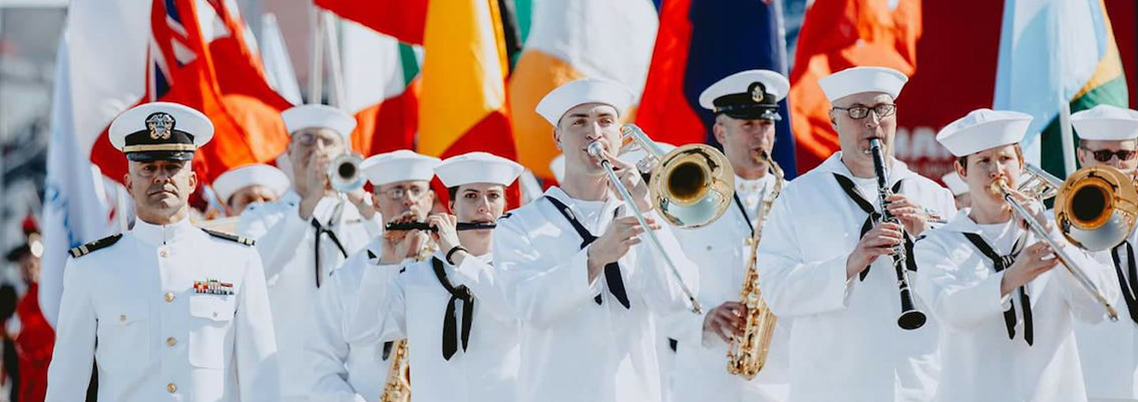 Image of Sailors playing instruments in front of a monument.